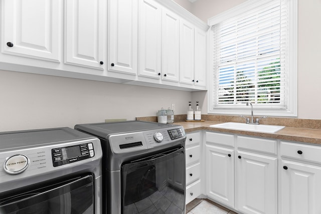 laundry room featuring light tile patterned floors, washer and clothes dryer, cabinet space, and a sink