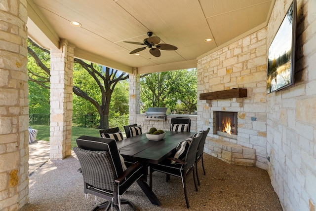 view of patio / terrace featuring area for grilling, a ceiling fan, an outdoor stone fireplace, and outdoor dining area