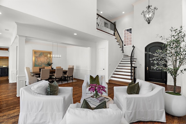 living area with stairway, a chandelier, ornamental molding, and a high ceiling