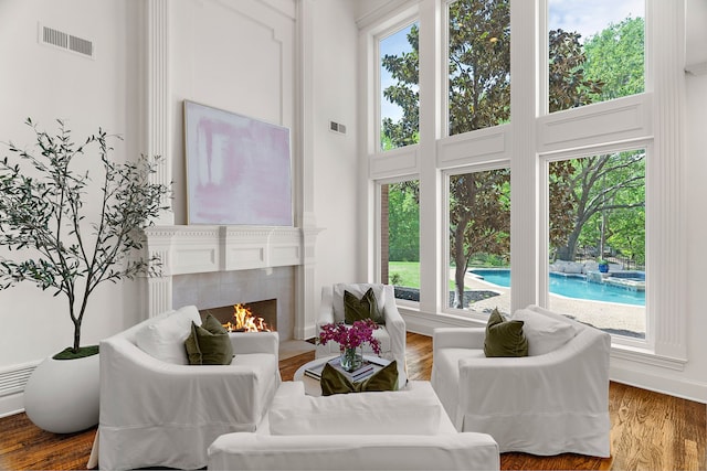 living area with visible vents, wood finished floors, a wealth of natural light, and a fireplace