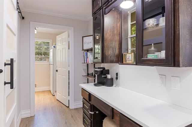 interior space featuring baseboards, light wood-style floors, and crown molding
