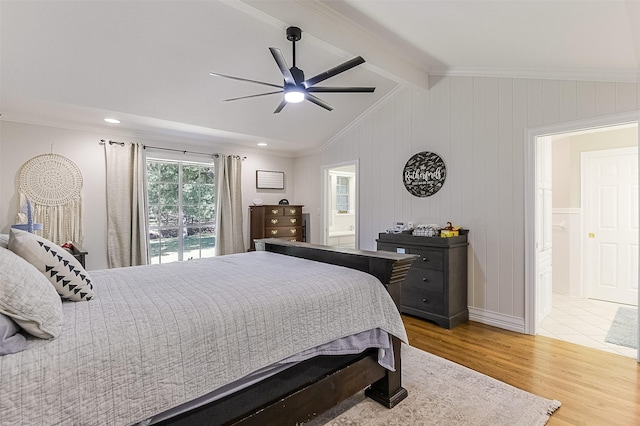 bedroom featuring crown molding, light wood finished floors, a ceiling fan, ensuite bath, and vaulted ceiling with beams