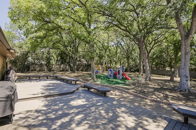 view of patio with playground community, a wooden deck, and a fenced backyard