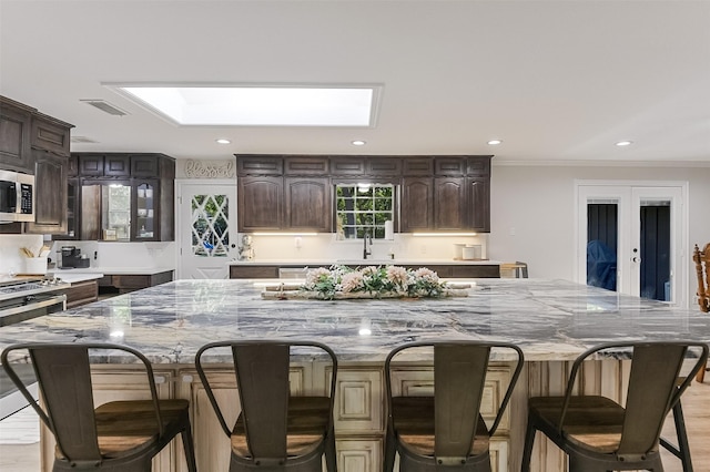 kitchen featuring recessed lighting, a skylight, visible vents, and light stone counters