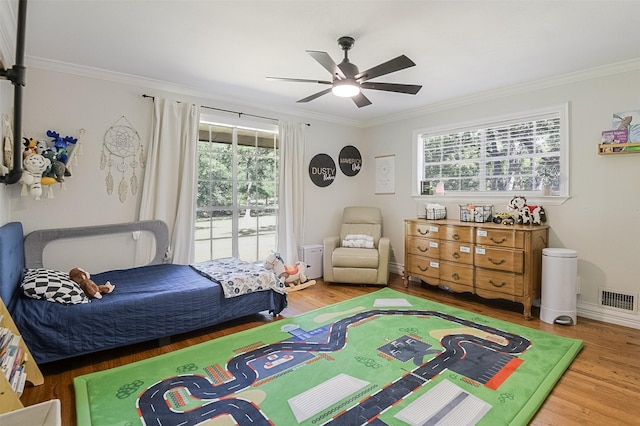 bedroom with wood finished floors, visible vents, and crown molding