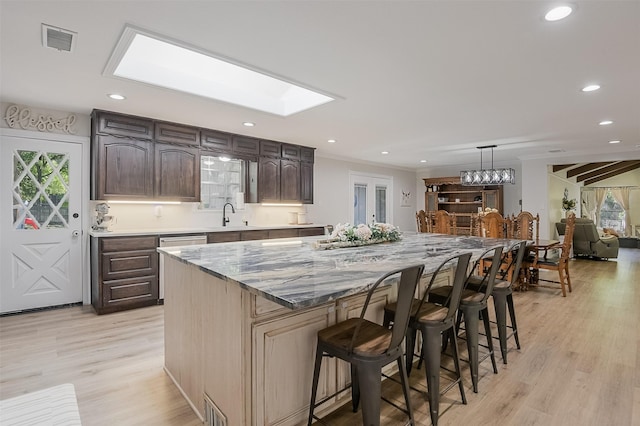 kitchen featuring visible vents, light wood-type flooring, a kitchen bar, and a kitchen island
