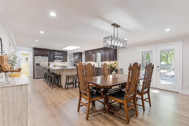 dining area with crown molding, recessed lighting, french doors, and light wood-style floors