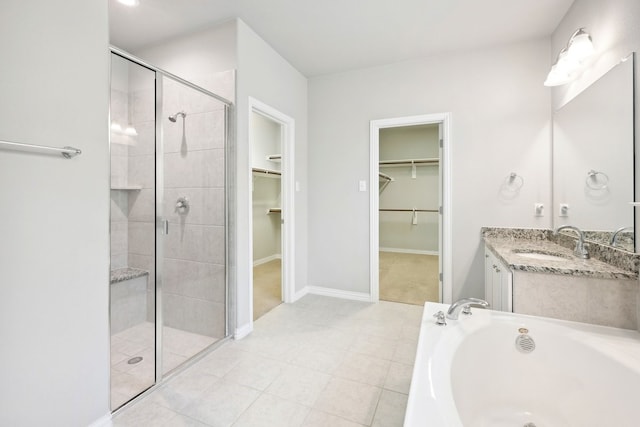 full bathroom with vanity, a bath, a stall shower, tile patterned flooring, and a spacious closet