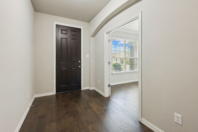 entryway featuring dark wood finished floors, baseboards, and arched walkways