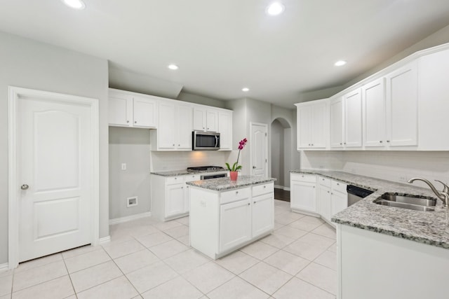 kitchen with stainless steel microwave, recessed lighting, arched walkways, and a sink