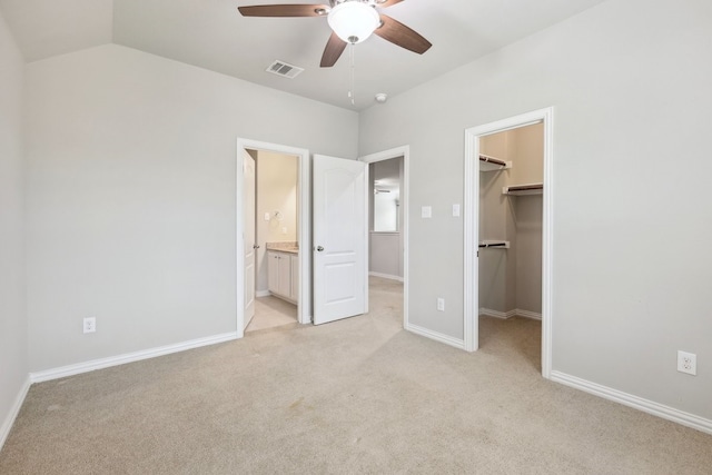 unfurnished bedroom featuring a walk in closet, visible vents, light colored carpet, and baseboards