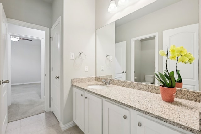 bathroom with toilet, tile patterned flooring, vanity, and baseboards