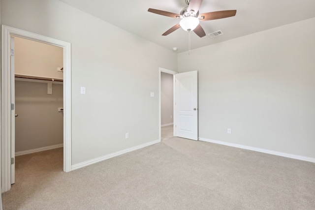 unfurnished bedroom with ceiling fan, visible vents, light carpet, baseboards, and a spacious closet