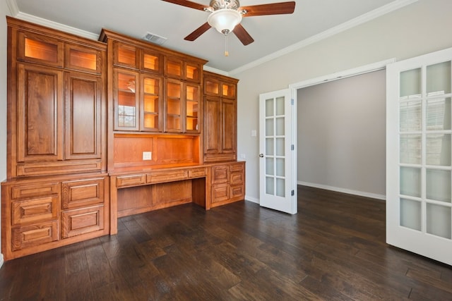 unfurnished office with built in desk, dark wood-style floors, ceiling fan, ornamental molding, and french doors