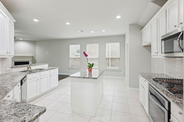 kitchen with white cabinetry, stainless steel appliances, backsplash, and a sink