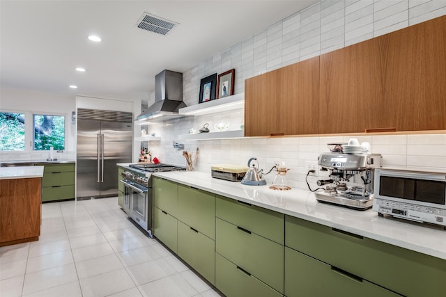 416 Crestwood Dr, Fort Worth, TX 76107 - kitchen with wall chimney range hood, green cabinets, backsplash, visible vents, and premium appliances