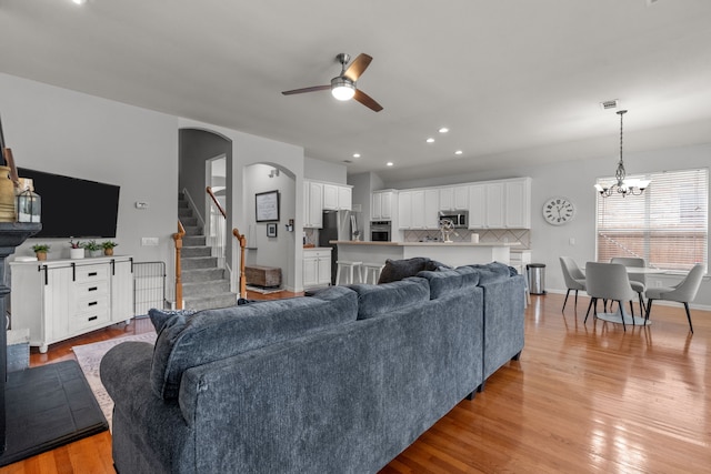2209 Graystone Ct, Keller, TX 76248 - living area with ceiling fan, light wood-style floors, a chandelier, stairway, and arched walkways