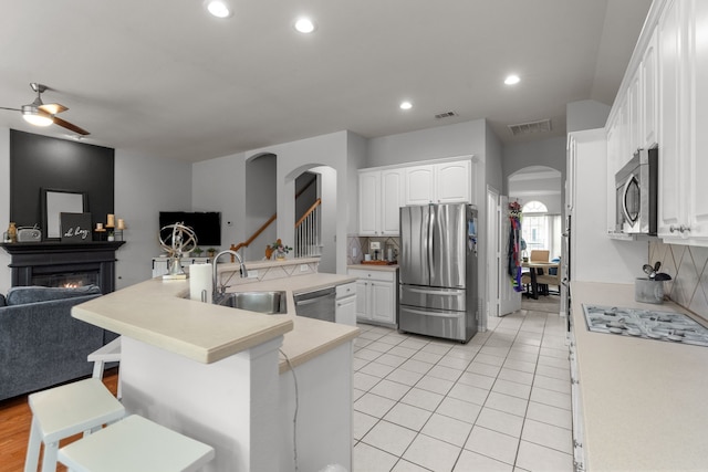 2209 Graystone Ct, Keller, TX 76248 - kitchen with stainless steel appliances, a sink, open floor plan, arched walkways, and a glass covered fireplace