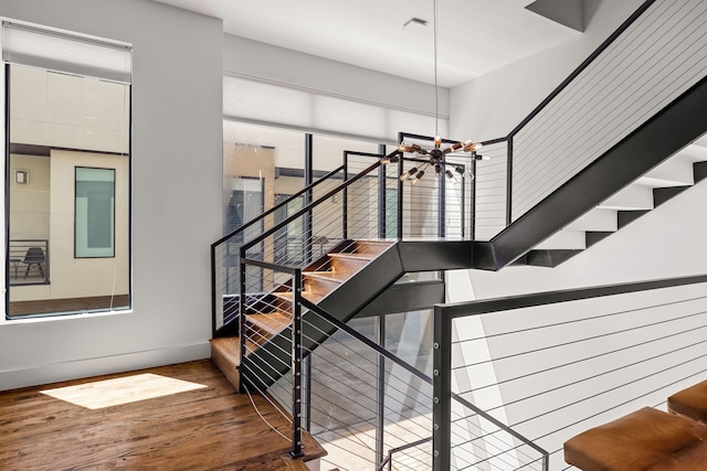 staircase featuring a chandelier, baseboards, and wood finished floors