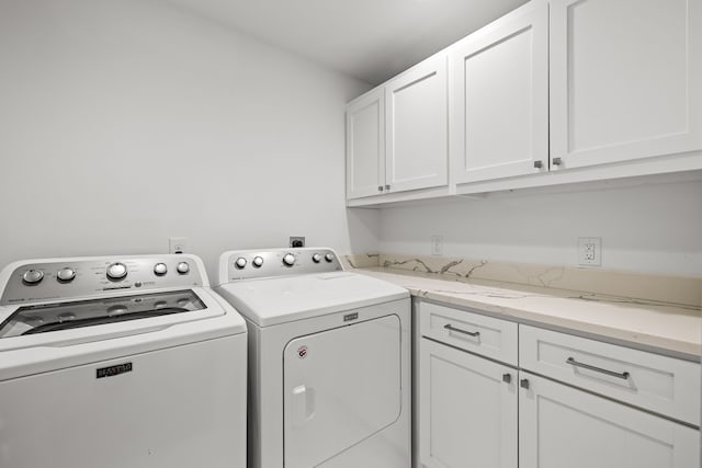 clothes washing area featuring washer and dryer and cabinet space