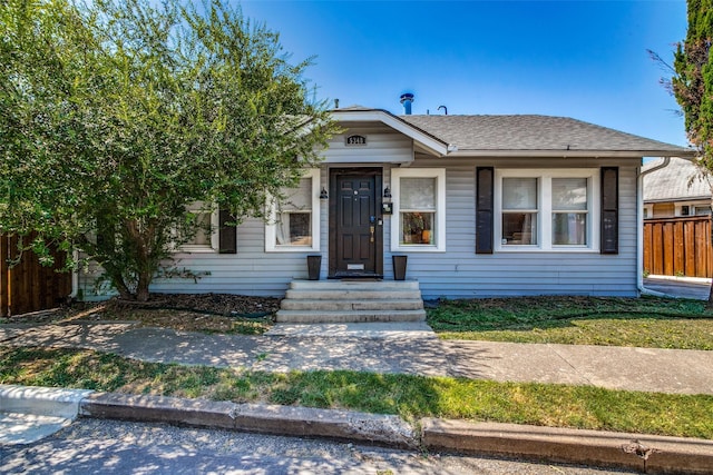 bungalow-style home with fence and a shingled roof