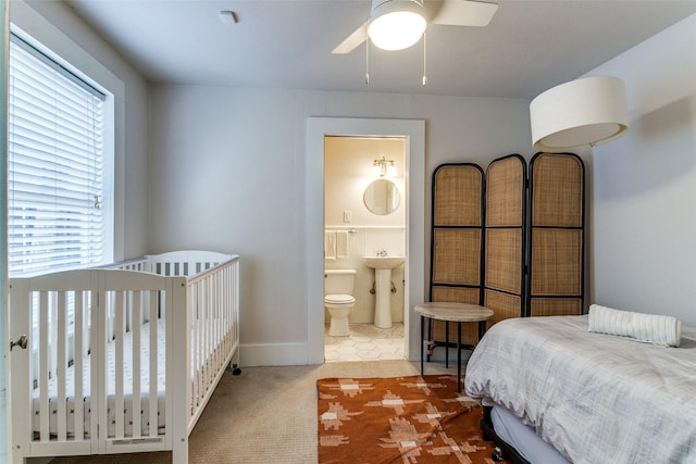bedroom with ensuite bathroom, carpet floors, and baseboards