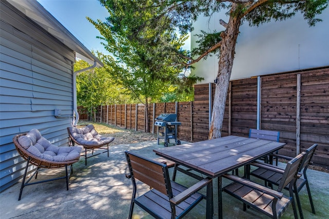 view of patio featuring outdoor dining space, a fenced backyard, and grilling area