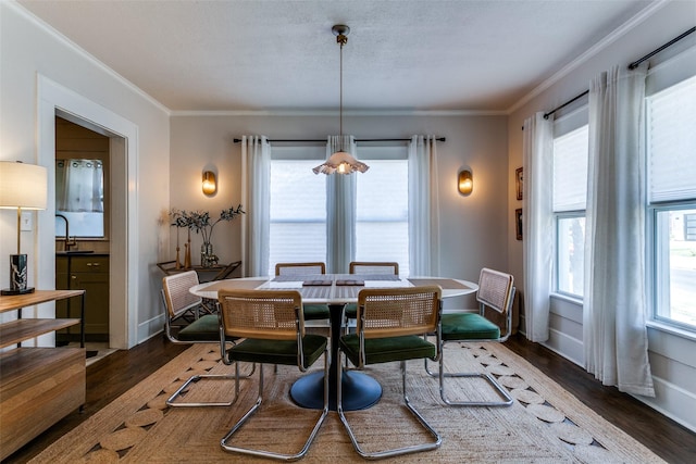 dining room with ornamental molding, baseboards, wood finished floors, and a healthy amount of sunlight