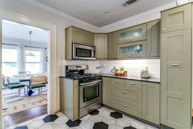 kitchen featuring appliances with stainless steel finishes, visible vents, ornamental molding, and glass insert cabinets