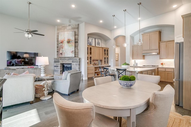 dining area featuring recessed lighting, wood finished floors, a ceiling fan, and a stone fireplace