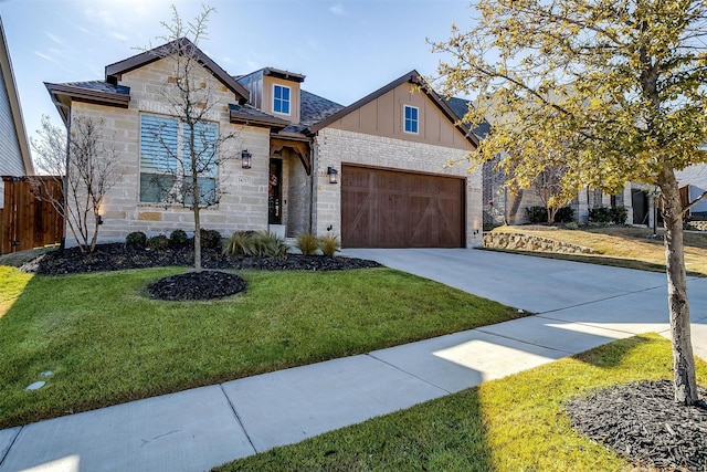 view of front of house with a front yard, concrete driveway, stone siding, and fence