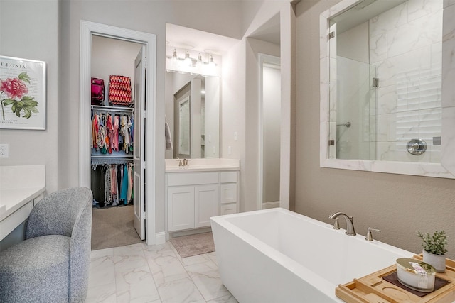 bathroom featuring a tile shower, a spacious closet, vanity, a freestanding bath, and marble finish floor