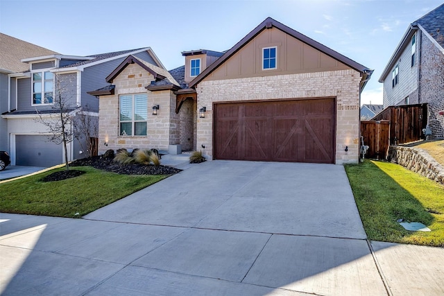 view of front of house with board and batten siding, fence, driveway, stone siding, and a front yard