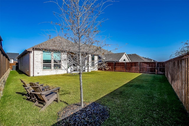 view of yard with a fenced backyard and central AC unit