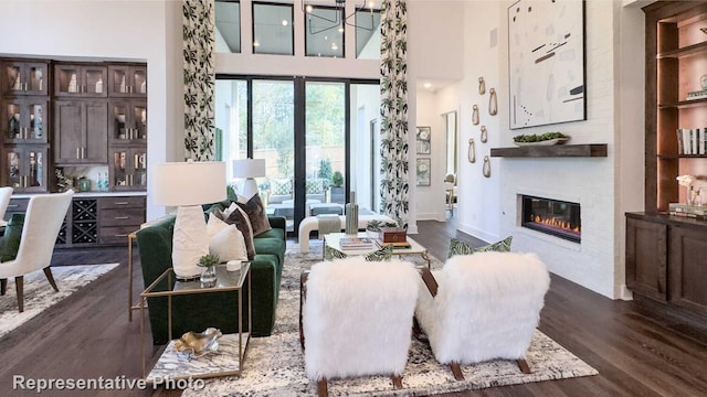 living area with a fireplace, baseboards, dark wood finished floors, and a high ceiling