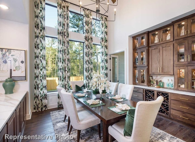 dining space featuring a high ceiling, an inviting chandelier, and dark wood finished floors