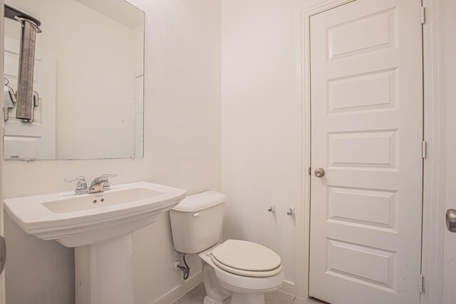 half bath featuring toilet, a sink, and baseboards