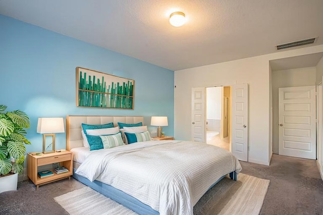 bedroom with visible vents, ensuite bath, and carpet