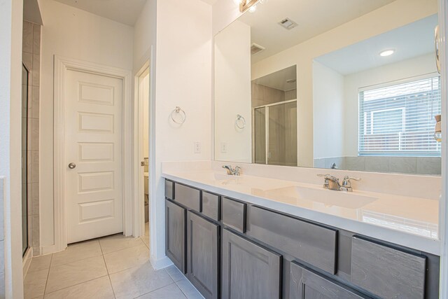 bathroom featuring tile patterned floors, double vanity, toilet, a sink, and a stall shower