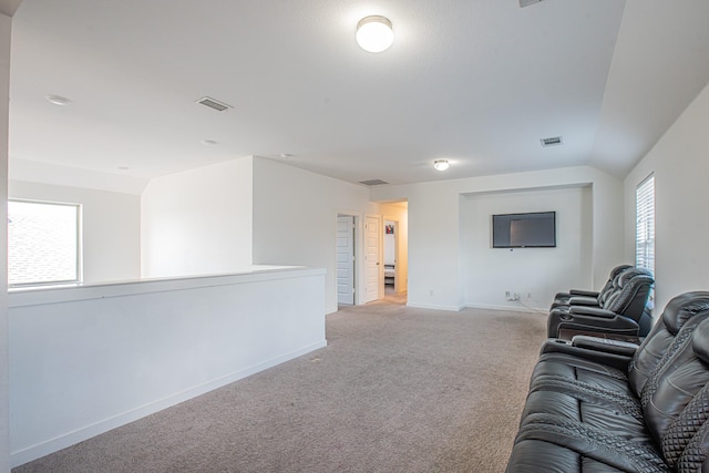 unfurnished living room with lofted ceiling, visible vents, light colored carpet, and baseboards