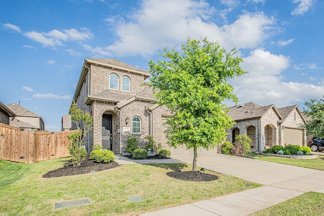 french country home featuring driveway, a front yard, fence, brick siding, and a garage