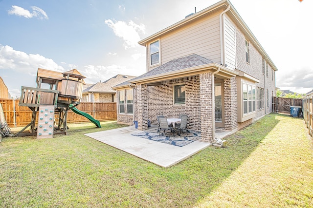 back of property with a playground, a patio area, a yard, brick siding, and a fenced backyard