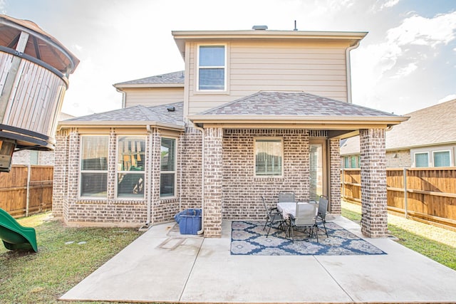 rear view of property with a lawn, a patio area, brick siding, and a fenced backyard