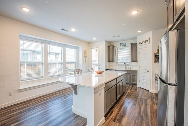 kitchen with visible vents, gray cabinetry, dark wood-type flooring, freestanding refrigerator, and a wealth of natural light