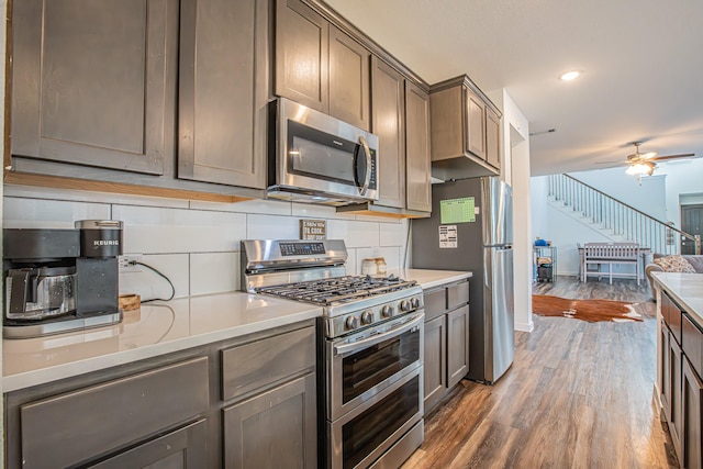 kitchen with stainless steel appliances, tasteful backsplash, a ceiling fan, light countertops, and wood finished floors