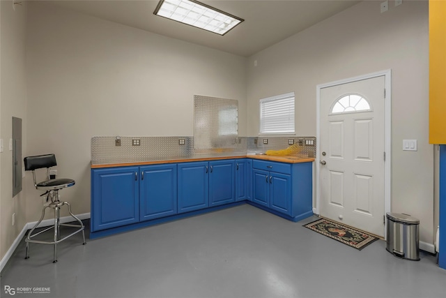 kitchen with backsplash, butcher block countertops, concrete floors, and blue cabinets