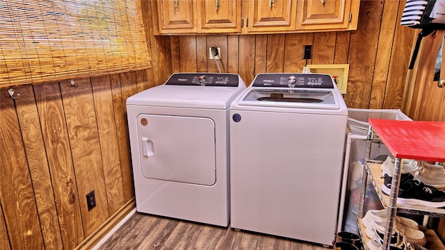 laundry room featuring dark wood-style floors, wood walls, cabinet space, and separate washer and dryer