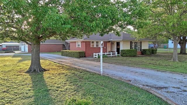 ranch-style home featuring driveway, a front lawn, covered porch, and brick siding