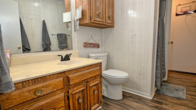 full bath with a shower with curtain, toilet, tile walls, wood finished floors, and vanity