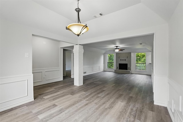 829 Hunters Creek Dr, Desoto, TX 75115 - unfurnished living room featuring wood finished floors, ornate columns, a decorative wall, a fireplace, and visible vents